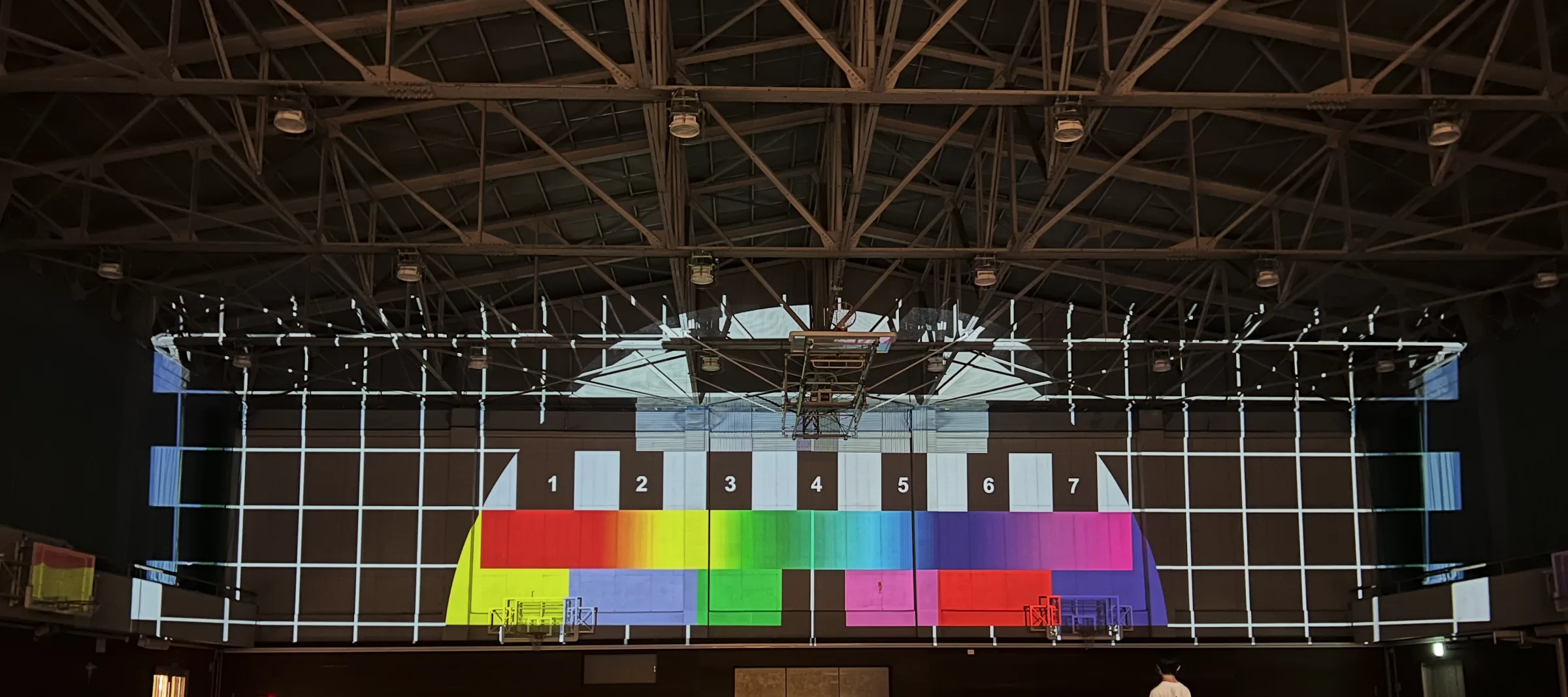 Color bars and a grid projected across the gymnasium walls for position and color alignment